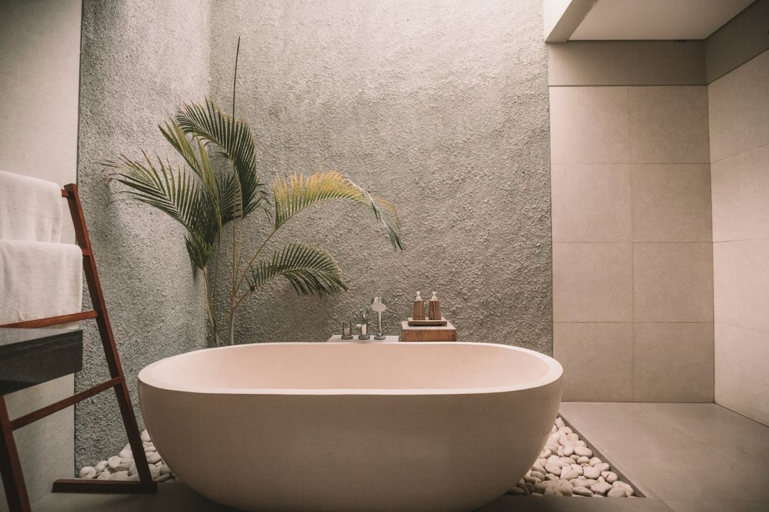 Freistehende Badewanne in einem großen Badezimmer mit einer Palme im Hintergrund