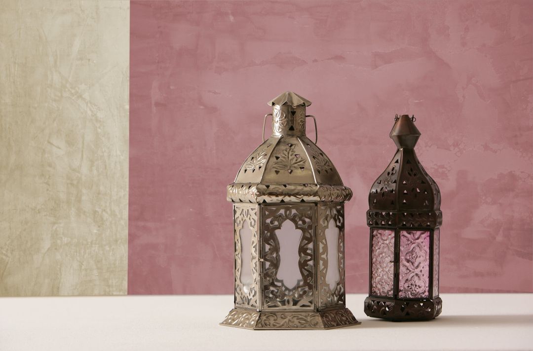 Lehm- und Kalkputz beim Hausbau: Vorteile und Tipps: zu sehen ist eine zweifarbige Wand mit Kalkputz in beige und altrosa. Im Vordergrund stehen zwei orientalische Laternen zur Deko