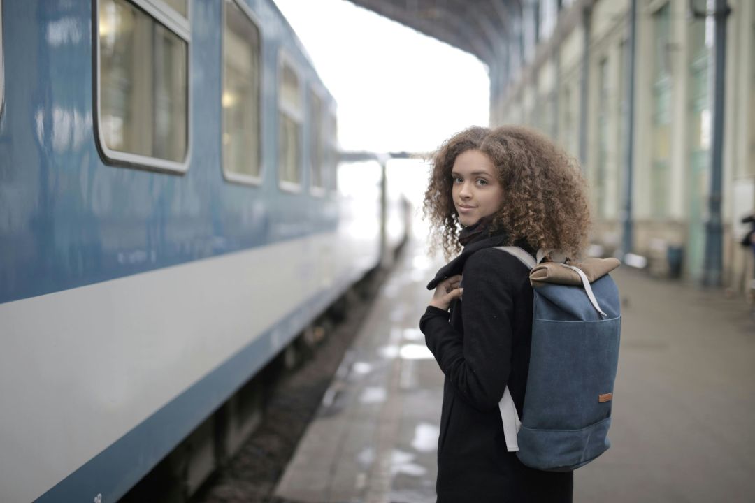 Frau steht vor einem Reisezug auf dem Bahnhof
