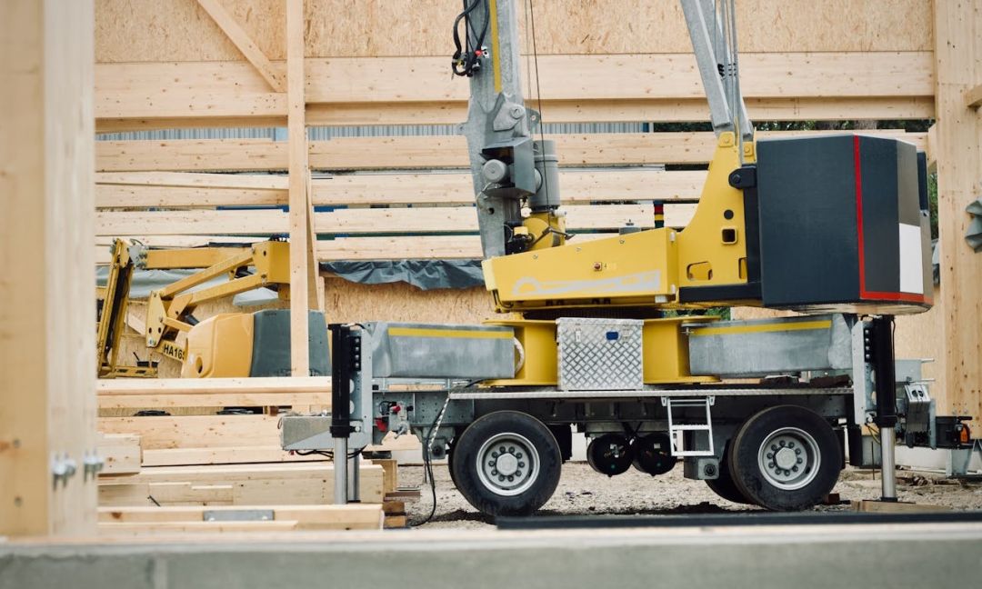 Baumaschinen stehen vor einem Holzhaus