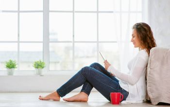 Frau sitzt behaglich auf dem Fußboden und liest