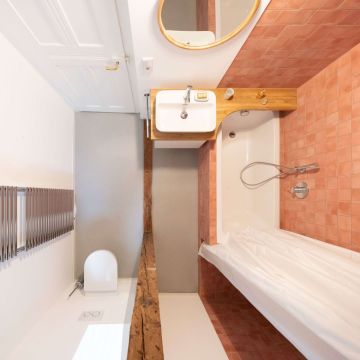 Durch die sichtbar belassenen Holzbalken im Bad bleibt die gründerzeitliche Raumaufteilung der Jugendstilwohnung erkenntlich.