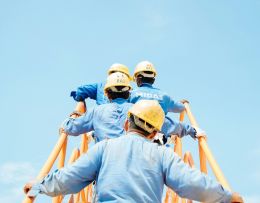 Arbeiter laufen über eine Leiter Richtung Himmel