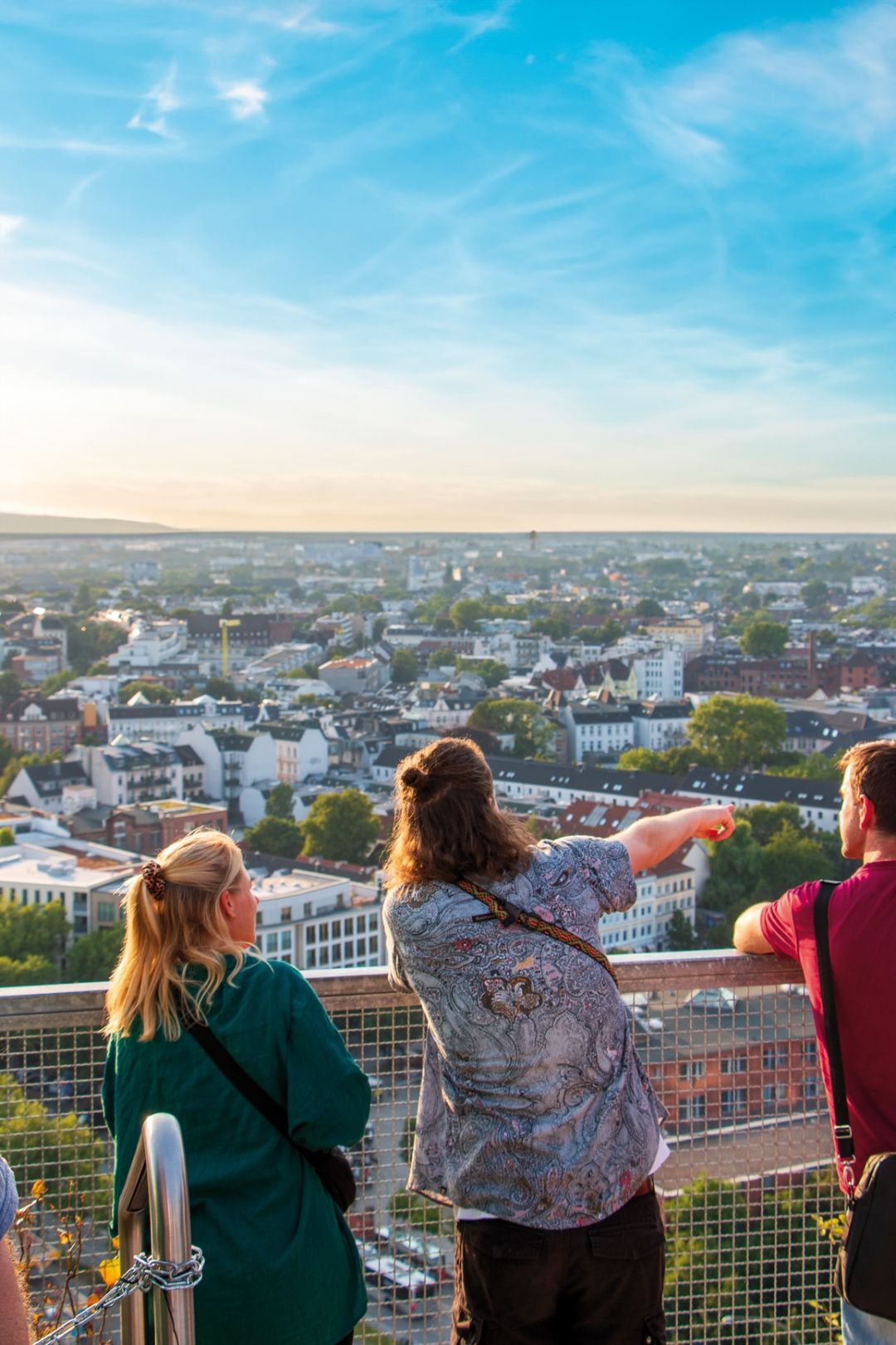 Menschen genießen den Ausblick über eine Stadtlandschaft, während sie von einer erhöhten Plattform aus nach unten schauen.