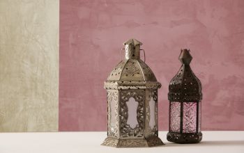 Lehm- und Kalkputz beim Hausbau: Vorteile und Tipps: zu sehen ist eine zweifarbige Wand mit Kalkputz in beige und altrosa. Im Vordergrund stehen zwei orientalische Laternen zur Deko