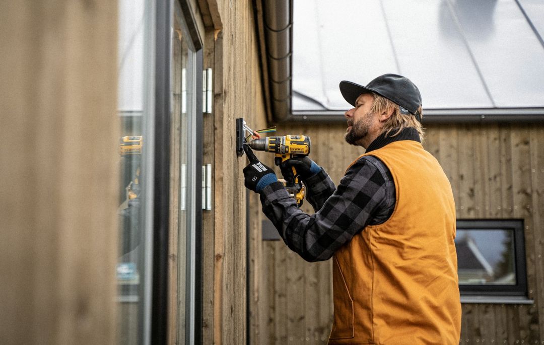 Ein Handwerker schraubt etwas an eine Holzwand