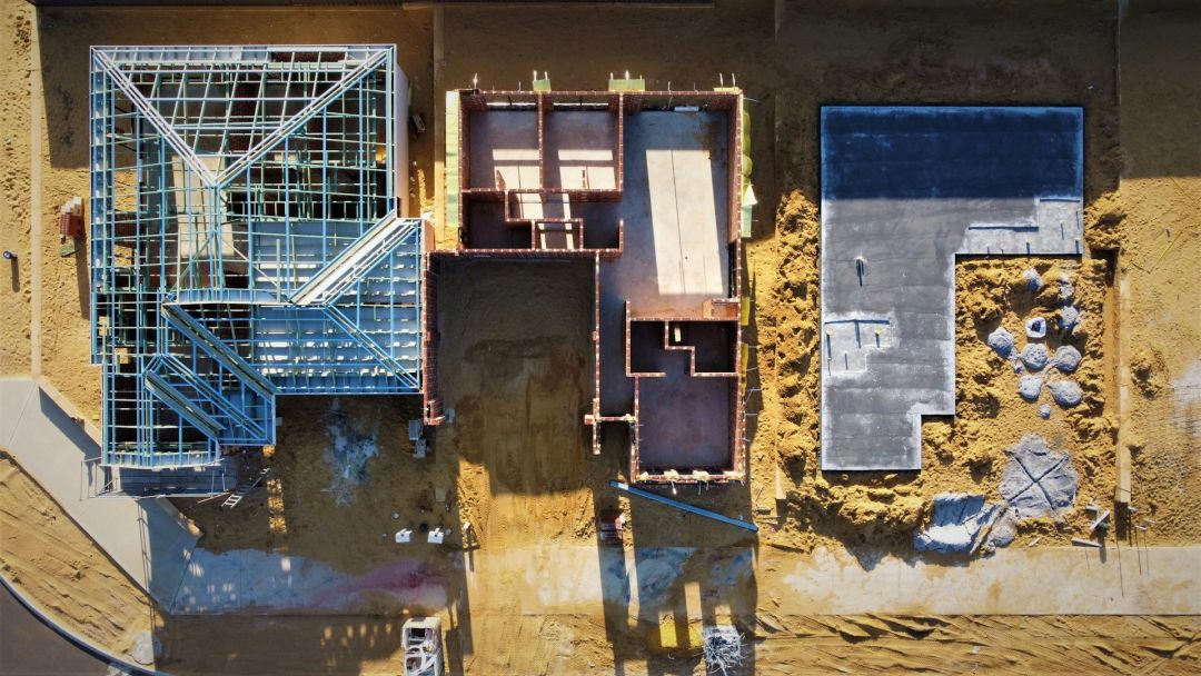 Neubau in drei Stadien: Links mit Dachgerüst, in Mitte im Rohbau, rechts das Fundament