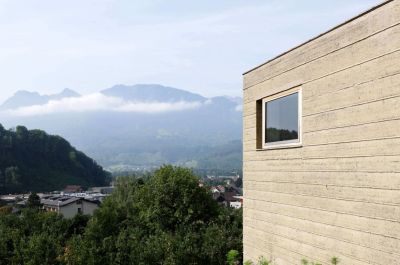 Haus aus Stampflehm vor Bergkulisse
