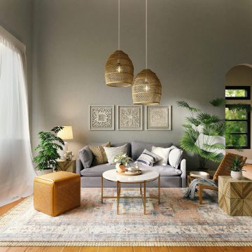 Nachhaltiges Wohnzimmer: zu sehen ist ein stylisches Wohnzimmer: graues Sofa, Lampen aus feinem Rattan, große Zimmerpflanzen und ein schöner Teppich.