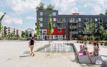 Grüne Wohnsiedlung mit Wasserspielen und sich treffenden Menschen