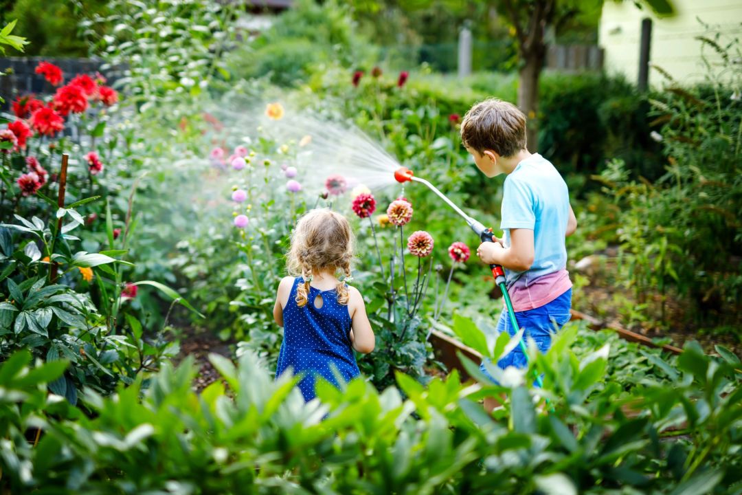 Zwei Kinder bewässern den Garten