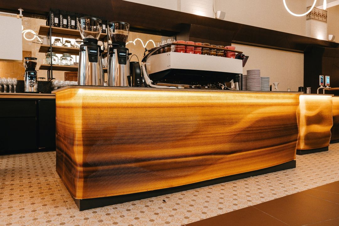 Eine stilvolle Kaffeebar mit modernen Kaffeemaschinen und einem leuchtenden Tresen, umgeben von einem eleganten Interieur.