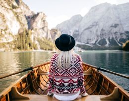 Frau von Hinten auf einem Ruderboot in idyllischer Landschaft sitzend