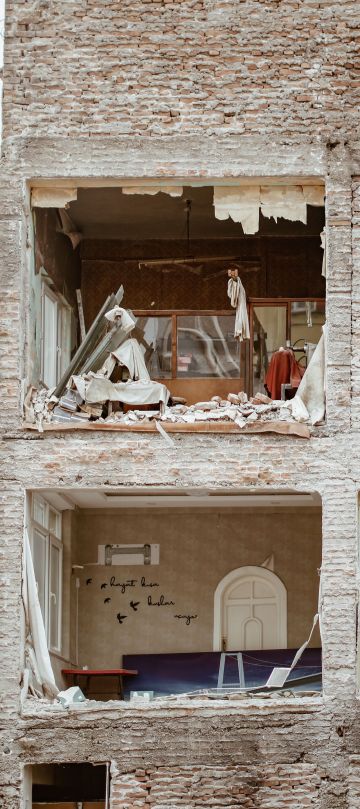Hausfassade, bei die Fenster herausgerissen wurden, man sieht noch die Möbel innen.
